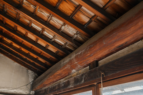 古民家の屋根裏に見える梁と雨漏りの跡が残る瓦屋根の内側